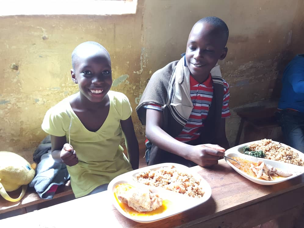 Two children smiling over plates of school lunch